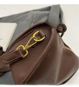 Close-up of golden hardware and dark brown litchi grain leather on a Boston bag
