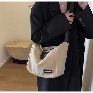 Detailed side view of beige nylon crossbody tote bag with adjustable black shoulder strap