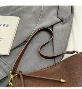 Detail of dark brown lychee leather texture and golden metal hooks on Boston bag strap