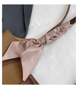 Detail of brown lychee grain leather tote bag featuring decorative silk scarf wrapped on handle