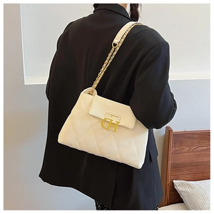 Gros plan du sac matelassé crème avec boucle en métal doré CH et bandoulière chaîne