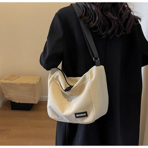 Close-up of a cream nylon tote bag featuring an adjustable black shoulder strap