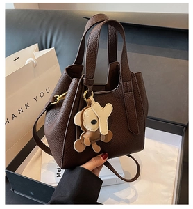 Detail of dark brown lychee grain leather tote bag with cute bear charm and thin strap