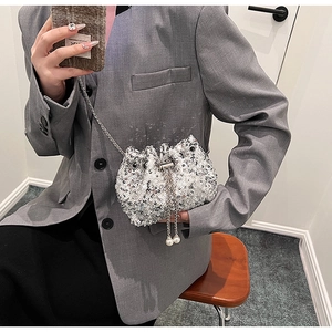 Sac seau à paillettes argentées avec chaîne et perles porté par un mannequin