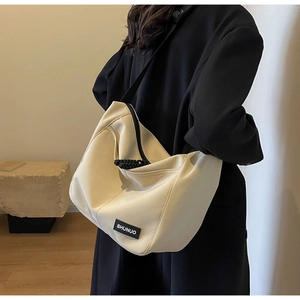 Close-up of beige nylon tote bag with black woven zipper puller and brand label