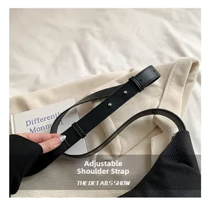 Detail shot of the adjustable leather strap with silver metal buckle on a black bag