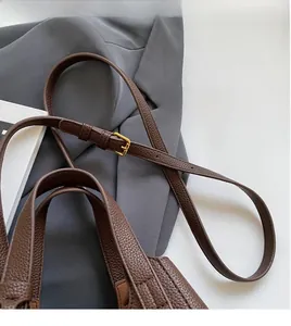 Detail of brown lychee grain leather bucket bag with adjustable gold buckle shoulder strap