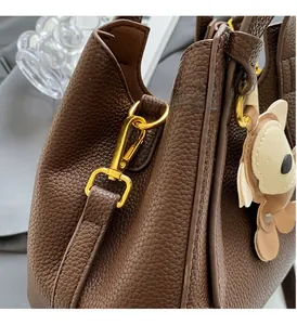 Close-up of premium gold hardware on a dark brown litchi pattern bucket bag with bear charm