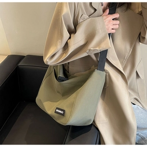 Close-up of army green nylon tote bag featuring durable wide black shoulder straps