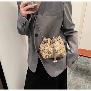 Détail du sac seau à paillettes champagne avec bandoulière chaîne et perles décoratives