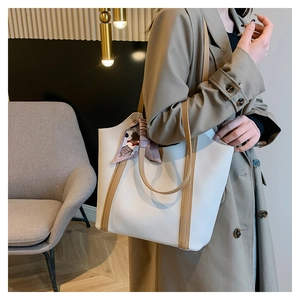 Close-up of white lychee grain tote bag featuring a decorative printed silk scarf on handle
