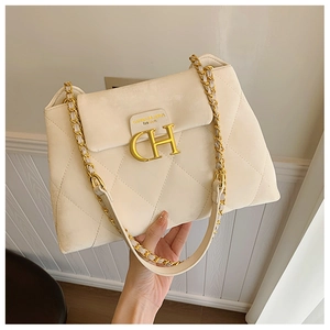 Gros plan sur le sac matelassé beige avec logo CH doré et bandoulière en chaîne