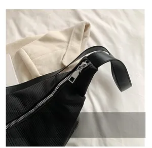 Detail showing high-quality silver metal zipper and black textured fabric of the bag
