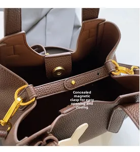 Detail of dark brown leather bucket bag showing invisible magnetic closure and gold hardware
