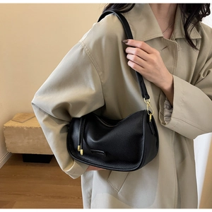 Close-up of black lychee grain leather underarm bag with premium gold hardware