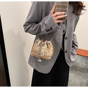 Détail d'un sac seau doré à paillettes avec cordon à perles et chaîne en métal argenté