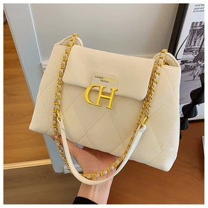 Détail d'un sac bandoulière beige matelassé avec boucle dorée CH et bandoulière chaîne