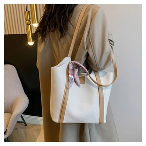 Detail of creamy and camel faux leather tote bag showing lychee grain and silk scarf handle