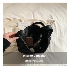 Internal capacity of large black corduroy shoulder bag showing phone and cosmetics