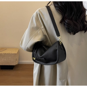 Detail of black pebbled leather Boston bag with gold hardware and wide shoulder strap