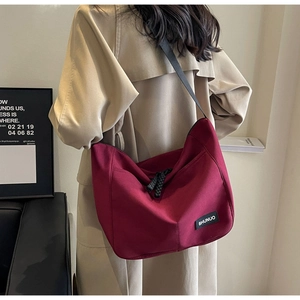 Burgundy nylon tote bag featuring a double zipper closure and logo detail on camera