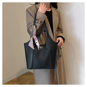 Detail of black pebbled leather tote bag with a pink decorative silk scarf on the handle