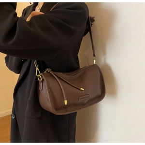 Detail of dark brown lychee leather Boston bag worn with a black wool coat
