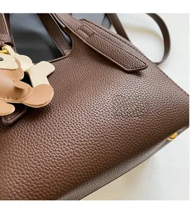Detail of dark brown pebble leather handbag with gold metal hardware and bear charm