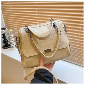 Dettaglio borsa a mano beige texture vintage con fibbia in metallo scuro e catena