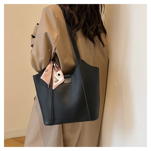 Detail of black pebbled leather tote bag featuring a pink floral silk scarf on the strap