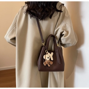 Detail of dark brown litchi grain leather bucket bag with a cute bear charm and Y detail