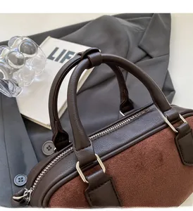 Detail of the dual-textured handbag featuring brown leather handles and silver D-ring hardware