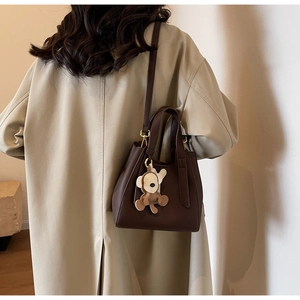 Detailed texture of dark brown lychee grain leather bucket bag with a small monkey charm