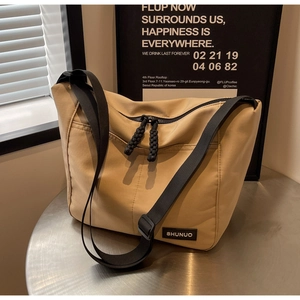 Detail of khaki nylon tote bag with black adjustable strap and woven zipper pulls