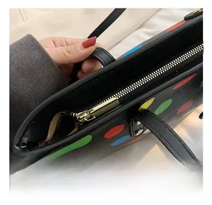 Détail du zip doré sur un sac cabas noir orné de pois colorés et poignée élégante