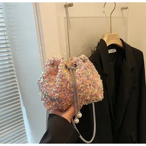 Détail d'un sac seau rose à paillettes avec cordon de serrage et grandes perles sur chaîne