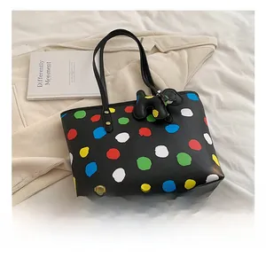 Détail d'un sac cabas noir avec pois colorés et pendentif en forme de chiot mignon