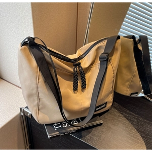Macro shot of khaki nylon tote bag featuring black woven pullers and adjustable strap