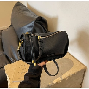 Detail of black pebbled leather Boston bag with premium gold-tone metal hardware