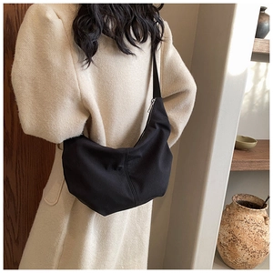 Detail of black crescent hobo bag in textured nylon showing draped look on model