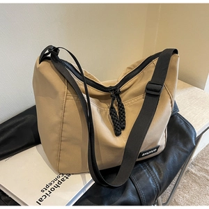 Close-up of khaki nylon tote bag featuring black zipper and woven rope puller detail