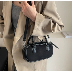 Model wearing a black matte crossbody bag with double handles and silver hardware
