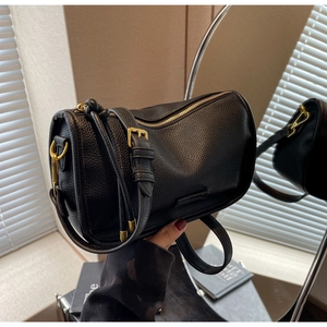 Macro shot of black litchi grain leather texture and gold hardware on a Boston bag