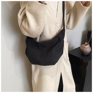Minimalist black half-moon hobo bag detail on wide shoulder strap and fabric texture
