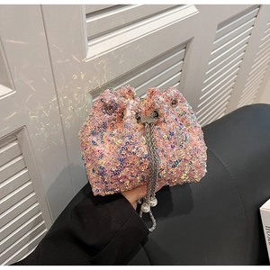 Détail d'un sac seau à paillettes avec breloque perle et bandoulière en chaîne argentée
