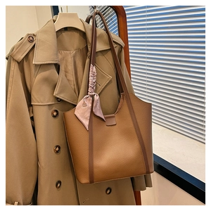 Close-up of brown pebbled leather tote bag with stylish floral silk scarf decoration