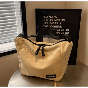 Detail of beige nylon tote bag with black zipper pullers and adjustable strap