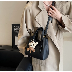 Detail of black pebble grain bucket bag featuring a brown bear and 'Y' letter charm