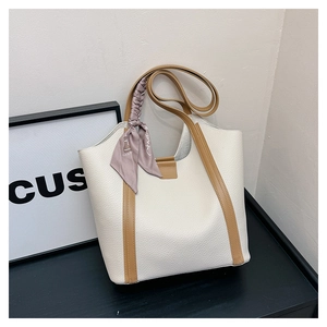 Close-up of white lychee leather tote bag with brown straps and decorative silk scarf