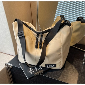 Close-up of beige nylon tote bag with dual zippers and woven cord pullers
